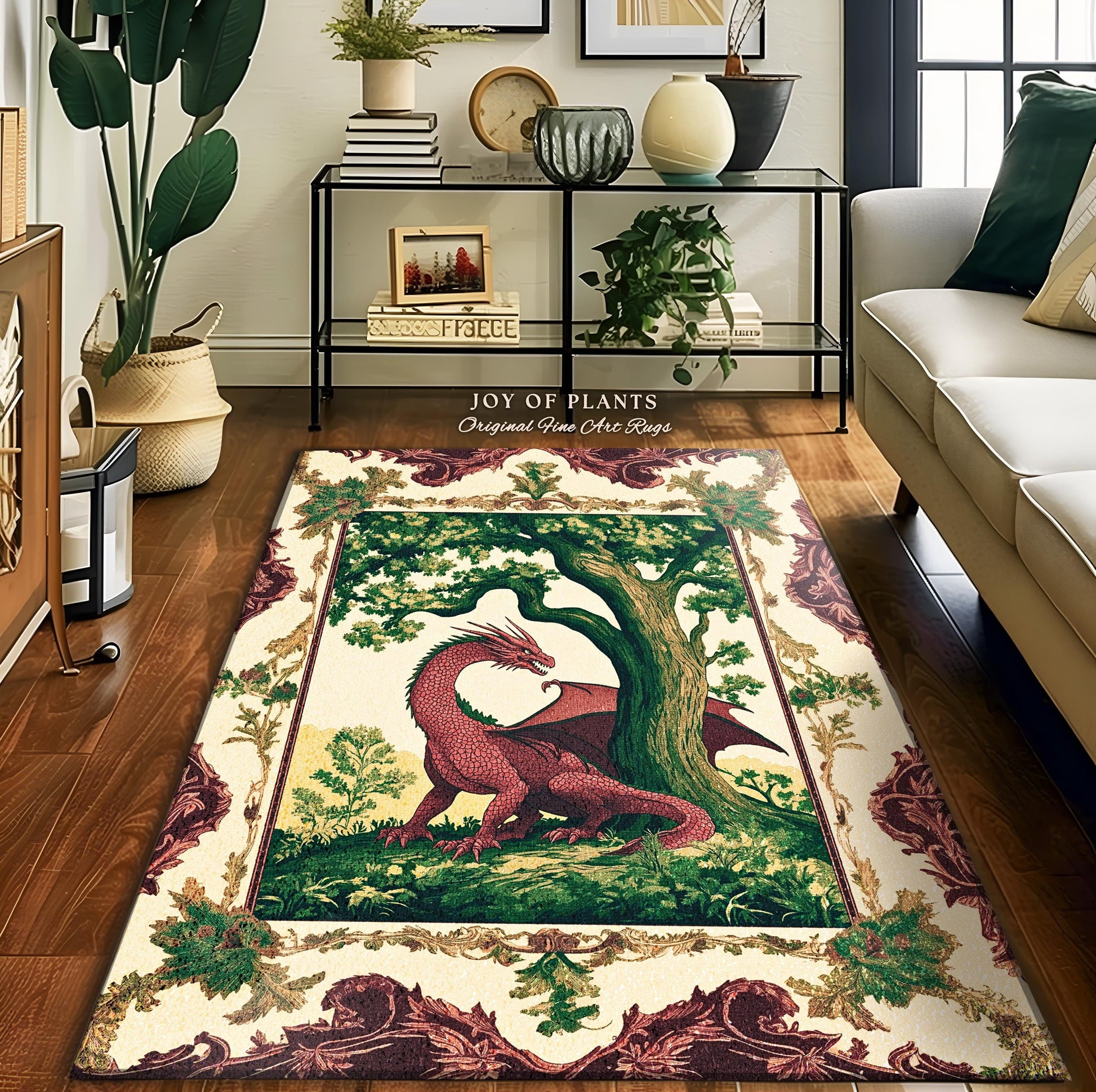 May include: A cream-colored rug features a vintage tapestry design. The central image depicts a red dragon beneath a large green oak tree. The rug's border showcases an ornate, burgundy-colored floral pattern. The text 'JOY OF PLANTS Original Fine Art Rugs' is subtly displayed above the rug. The rug is displayed on a hardwood floor in a living room setting.