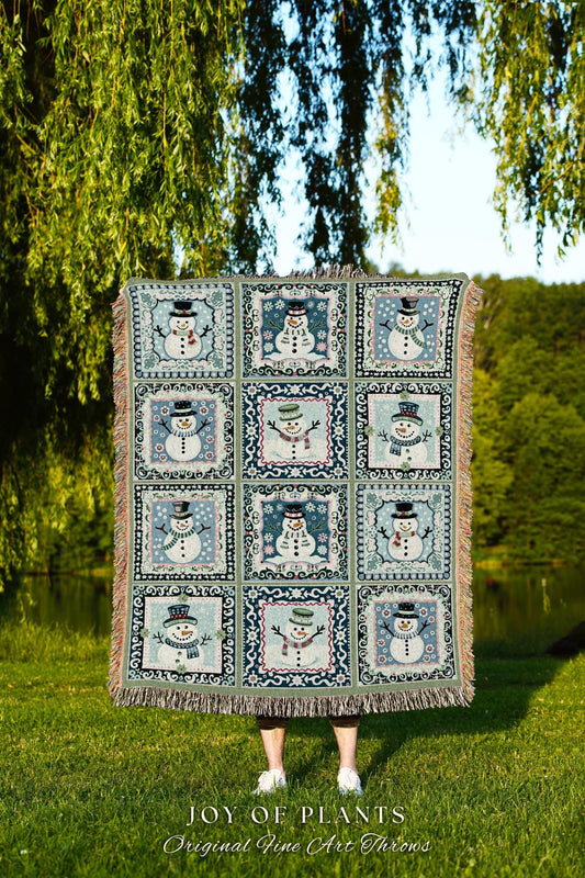 May include: A cozy woven throw blanket features a patchwork design of 12 framed snowman illustrations. Each square shows a unique snowman in varying poses and hats against a muted blue and green background. The blanket has fringed edges and is made of a soft, textured fabric. The text 'JOY OF PLANTS Original Fine Art Throws' is displayed at the bottom.
