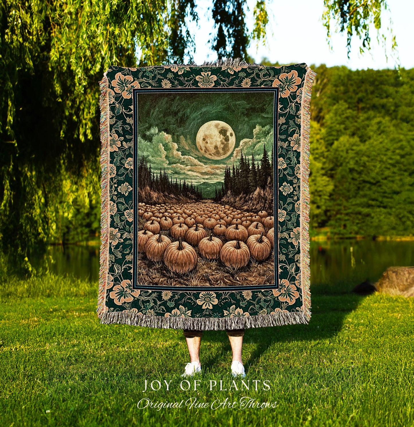 May include: A dark green tapestry throw blanket with a floral border and a central image of a full moon over a field of pumpkins. The artwork features a night scene with a forest and a cloudy sky. The words 'JOY OF PLANTS Original Fine Art Throws' are at the bottom.