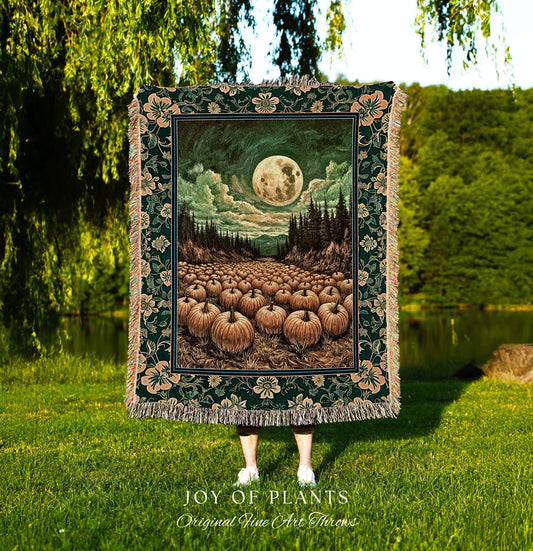 May include: A dark green tapestry throw blanket with a floral border and a central image of a full moon over a field of pumpkins. The artwork features a night scene with a forest and a cloudy sky. The words 'JOY OF PLANTS Original Fine Art Throws' are at the bottom.