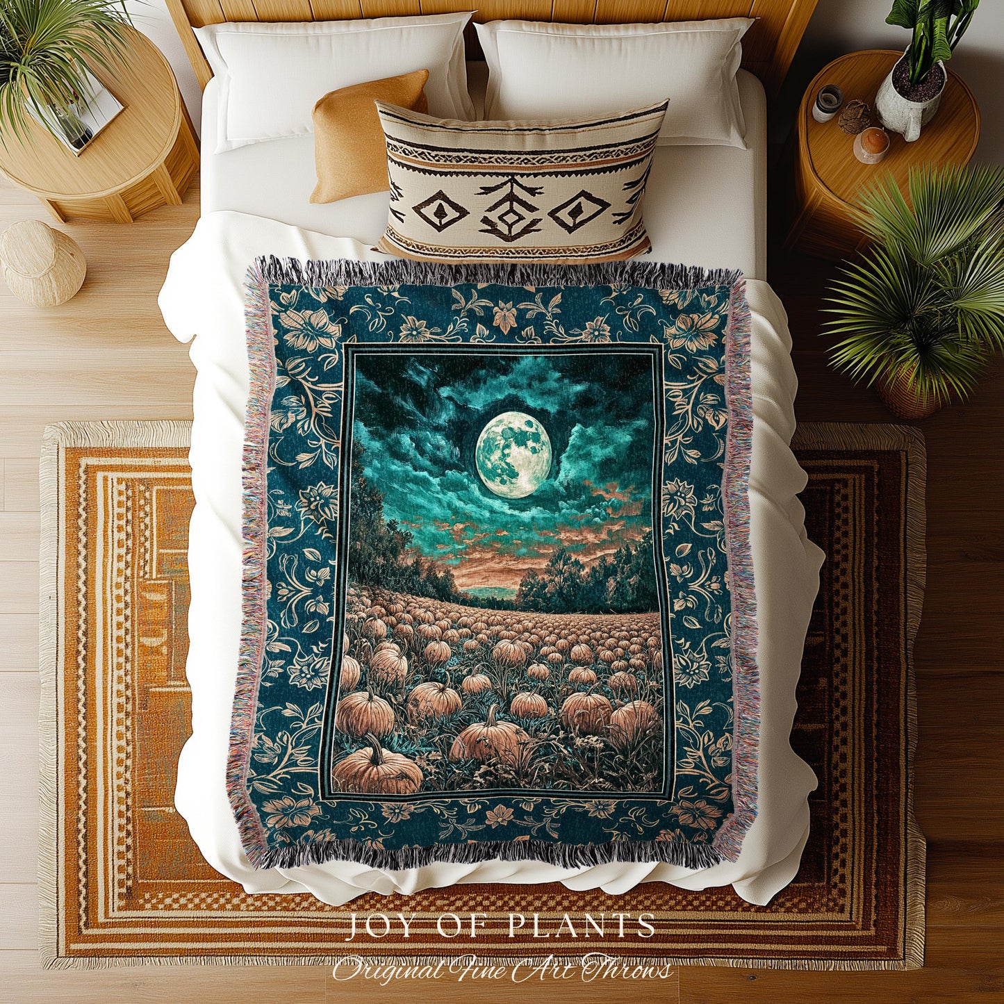 May include: A teal throw blanket with a full moon and pumpkin field design. The blanket has a fringed edge and a floral border. The scene depicts a full moon in a teal sky above a field of pumpkins. The blanket is on a bed with white bedding and a patterned pillow.