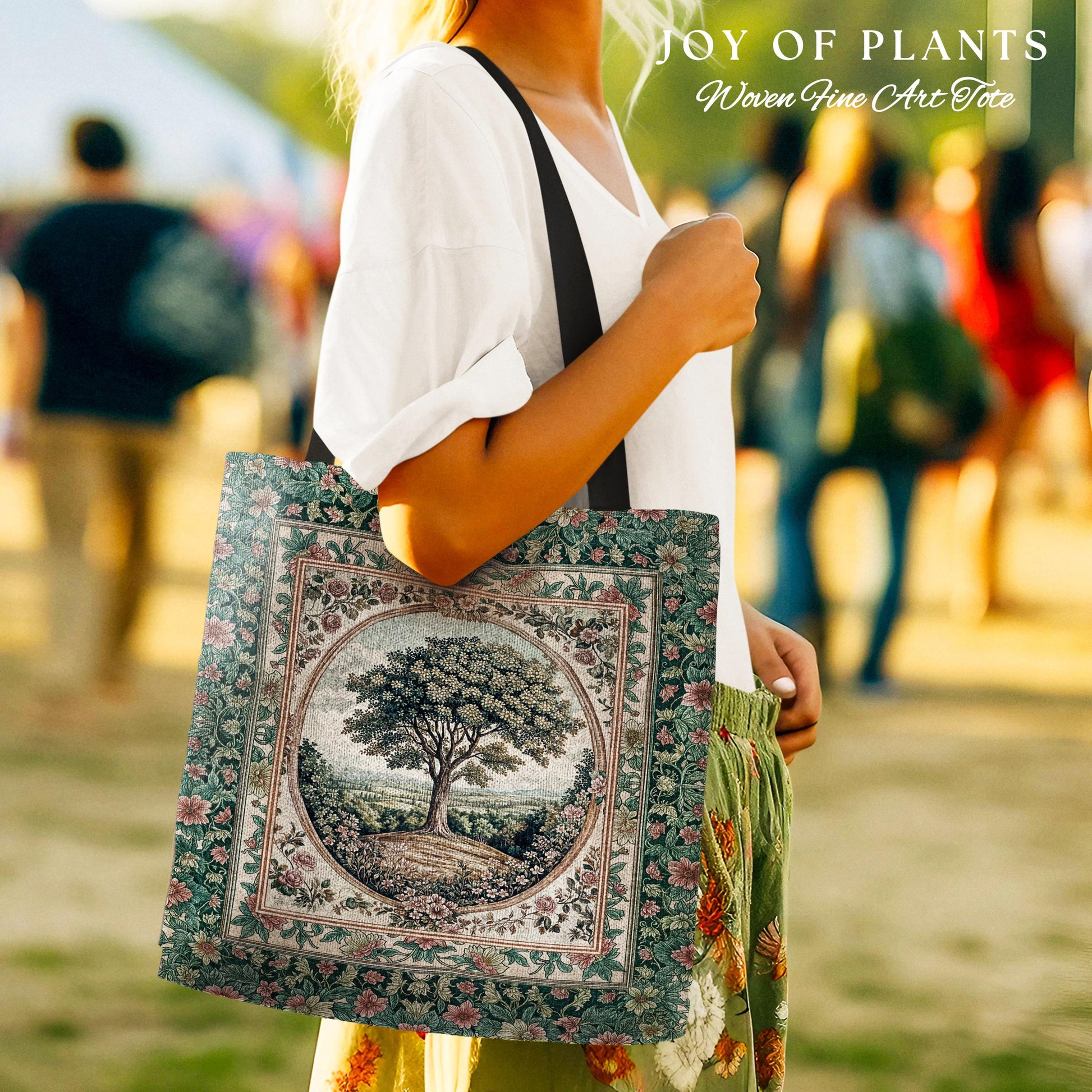 May include: A square tote bag with a tree design. The bag features a detailed illustration of a tree in a circular frame, surrounded by floral patterns. The bag has a green and beige color scheme with a black strap. Text at the top reads 'JOY OF PLANTS' and 'Woven Fine Art Tote'.