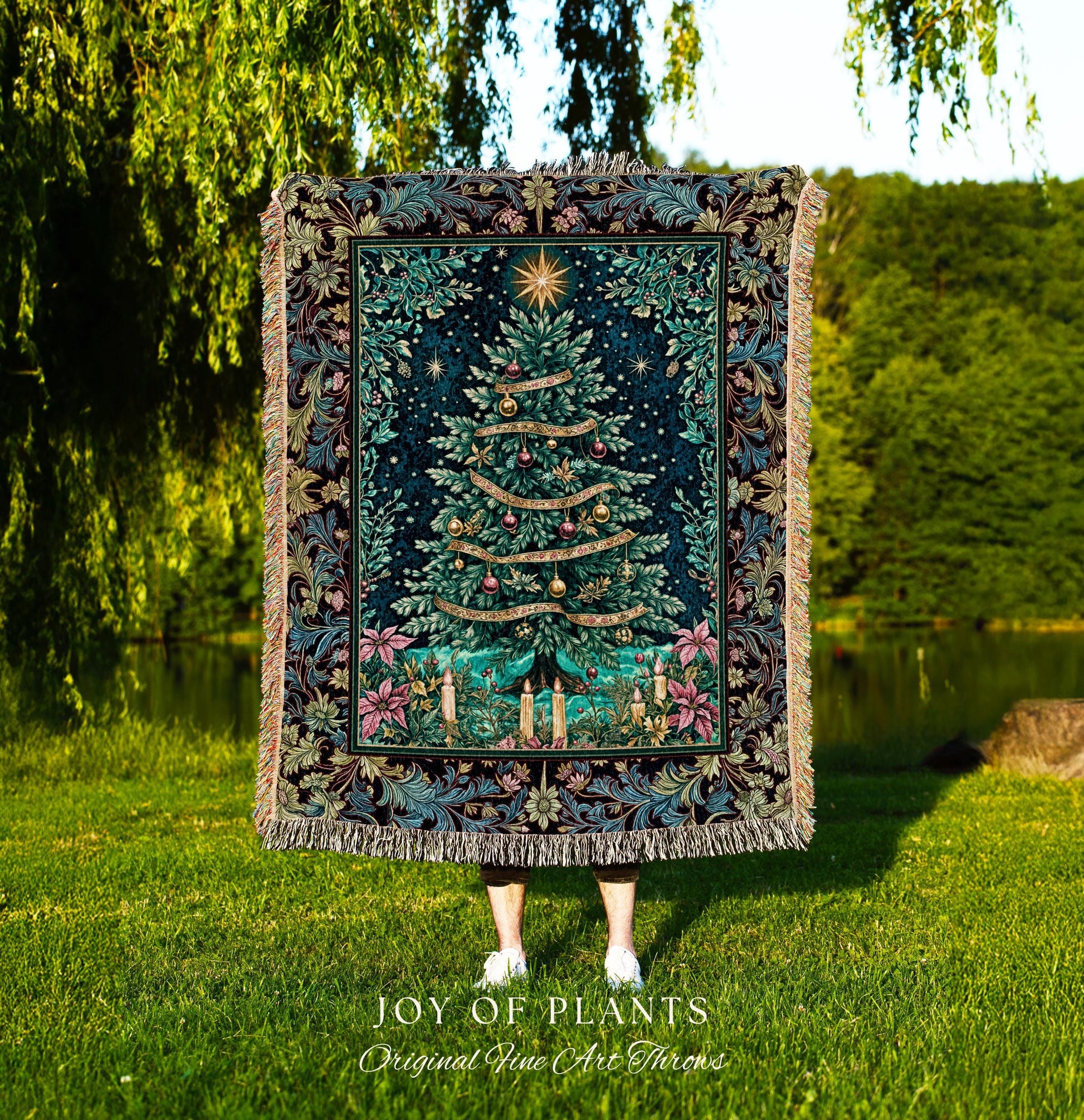 May include: A tapestry throw blanket featuring a Christmas tree design. The tree is green with gold ornaments and ribbons, set against a dark blue background with a star at the top. The border has floral and leaf patterns in shades of blue, green, and pink. The blanket has a fringed edge and the words 'JOY OF PLANTS Original Fine Art Throws' are at the bottom.