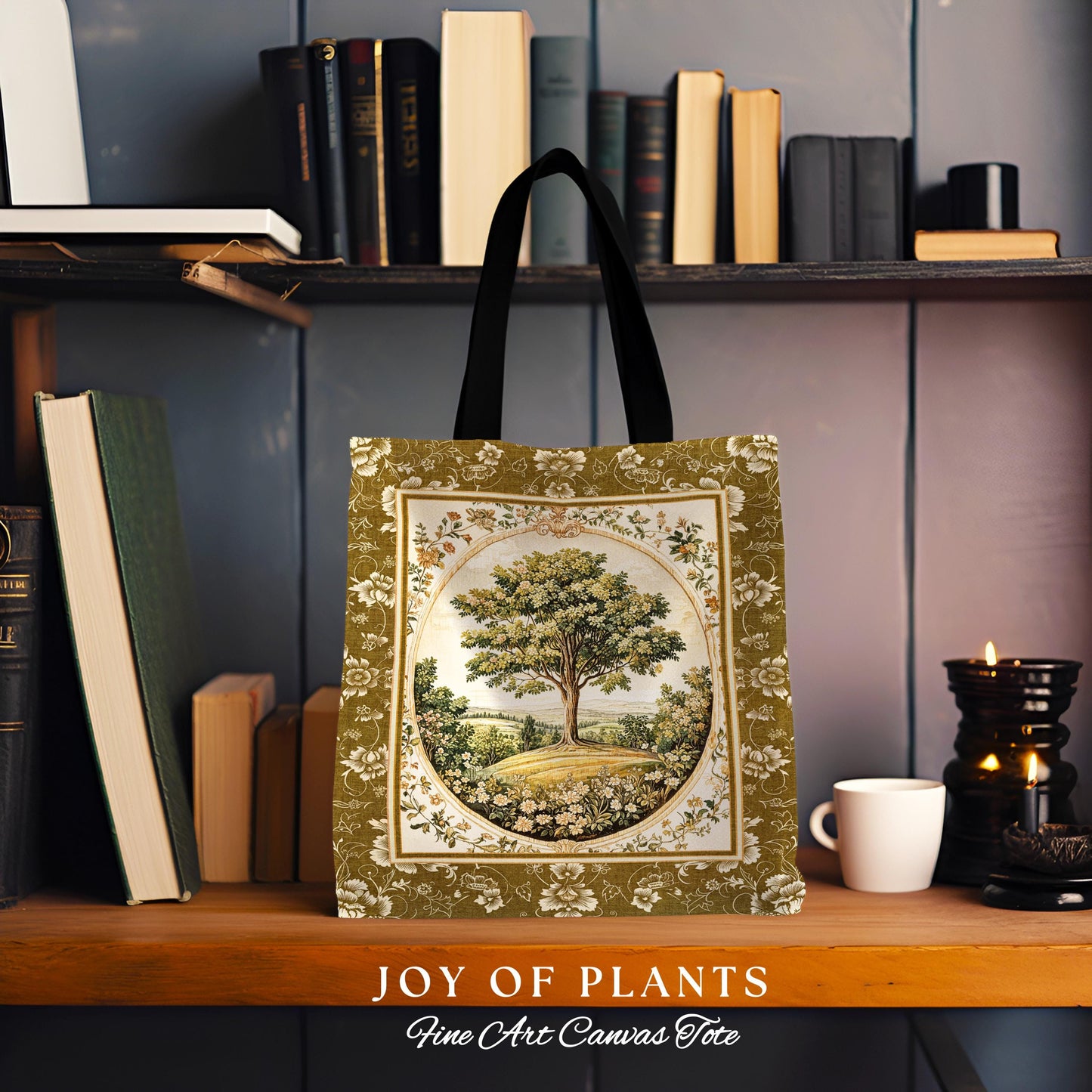 May include: Canvas tote bag featuring a tree landscape design. The bag has a black handle and a rectangular shape with a floral border. The design is in a circular frame with a tree in the center, surrounded by a field and sky. Text at the bottom reads 'JOY OF PLANTS Fine Art Canvas Tote'.