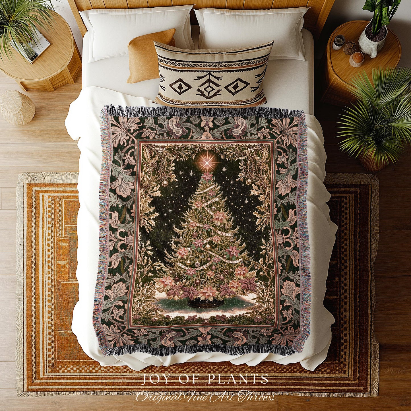 May include: A Christmas tree tapestry throw blanket on a bed. The blanket features a detailed Christmas tree design with ornaments and a star on a dark background. The border has floral and leaf patterns in shades of green and pink. The blanket is fringed and the bed has white sheets and pillows.