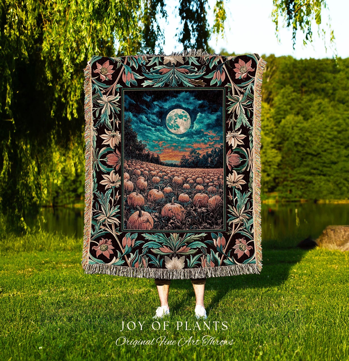 May include: A decorative throw blanket featuring a detailed, colorful design. The blanket showcases a nighttime landscape with a full moon over a pumpkin field. The border has floral and leaf patterns in teal, pink, and black. The blanket is labeled &#39;JOY OF PLANTS Original Fine Art Throws&#39;.