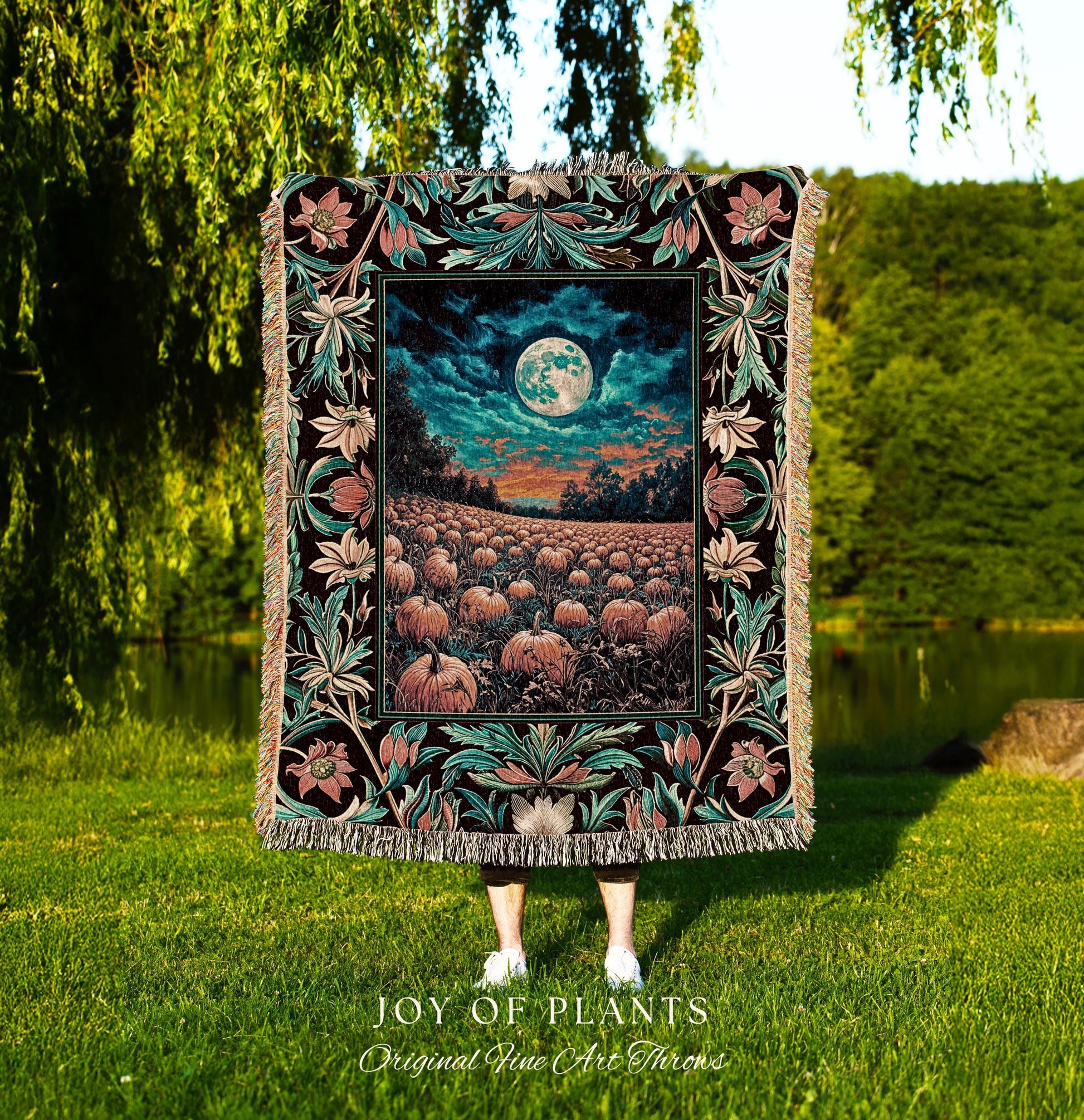 May include: A decorative throw blanket featuring a detailed, colorful design. The blanket showcases a nighttime landscape with a full moon over a pumpkin field. The border has floral and leaf patterns in teal, pink, and black. The blanket is labeled &#39;JOY OF PLANTS Original Fine Art Throws&#39;.