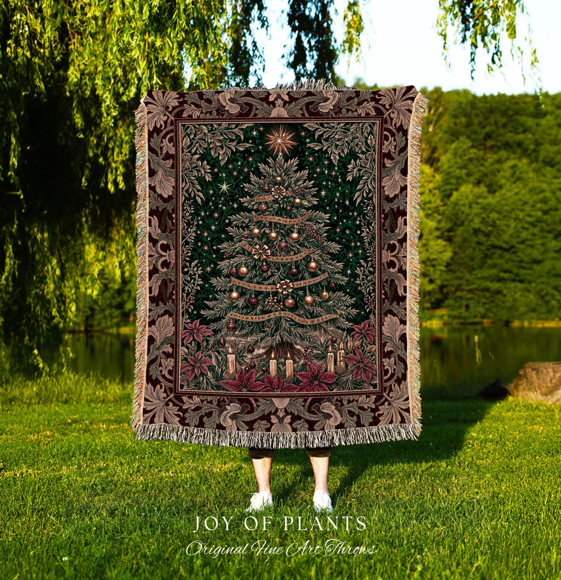 May include: A tapestry throw blanket featuring a detailed Christmas tree design. The tree is adorned with ornaments and candles, set against a dark green background. The blanket has a decorative border with floral and leaf patterns in shades of brown and green. The words &#39;JOY OF PLANTS&#39; and &#39;Original Fine Art Throws&#39; are at the bottom.