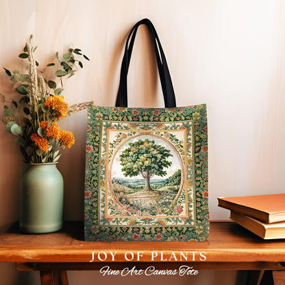 May include: A canvas tote bag featuring a tree illustration within a floral frame. The bag has black handles and a rectangular shape. The artwork showcases a tree in a landscape with a green and gold color scheme. The words &#39;JOY OF PLANTS&#39; and &#39;Fine Art Canvas Tote&#39; are printed at the bottom.