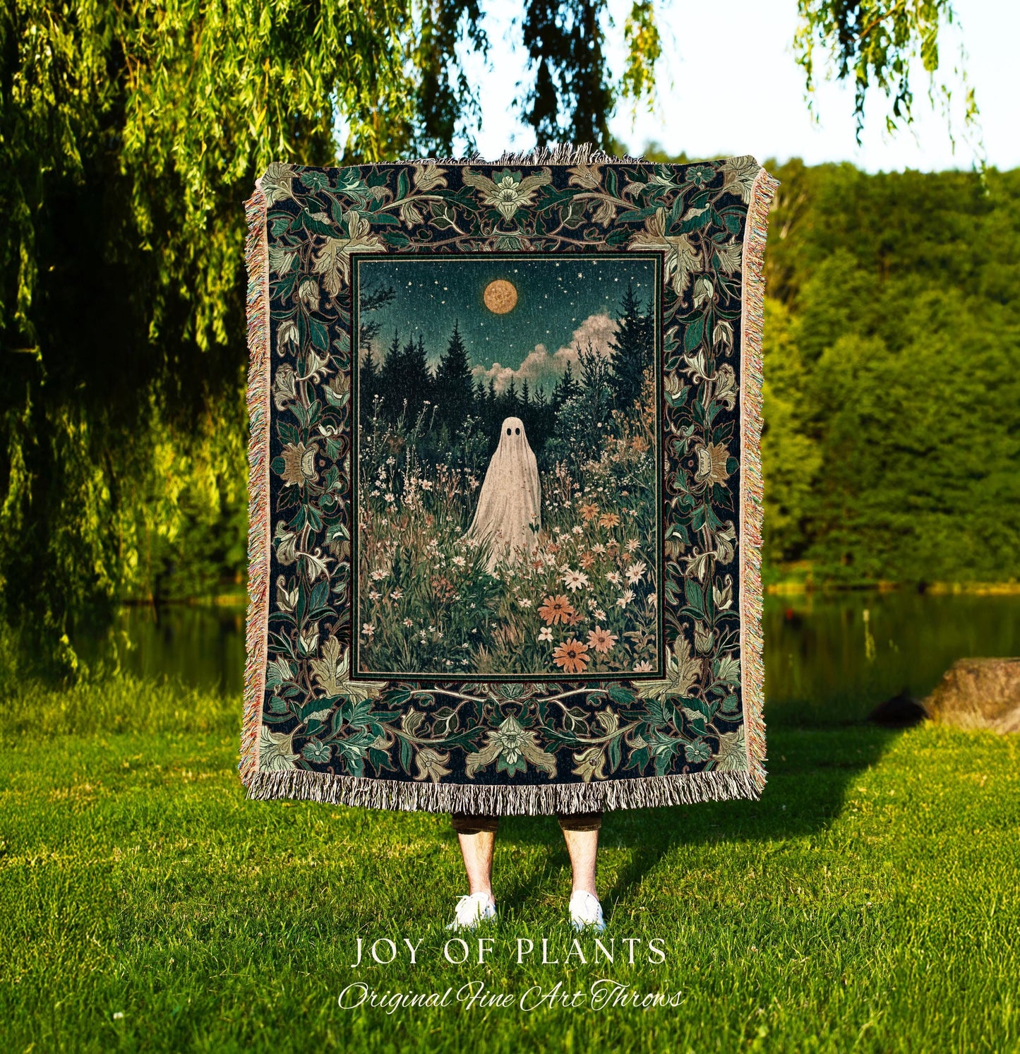 May include: A tapestry throw blanket featuring a night scene with a ghost figure in a field of flowers under a starry sky and a full moon. The blanket has a dark green border with floral patterns and fringe. The text &#39;JOY OF PLANTS Original Fine Art Throws&#39; is at the bottom.