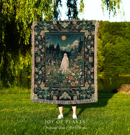 May include: A tapestry throw blanket featuring a night scene with a ghost figure in a field of flowers under a starry sky and a full moon. The blanket has a dark green border with floral patterns and fringe. The text &#39;JOY OF PLANTS Original Fine Art Throws&#39; is at the bottom.