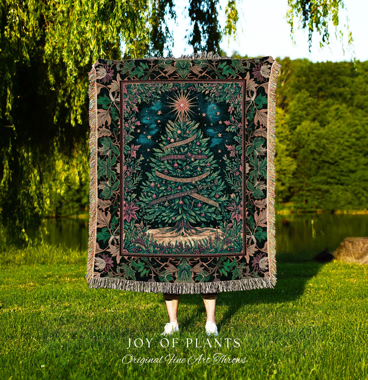May include: A tapestry throw blanket with a Christmas tree design. The tree is green with a star on top and ribbons with text. The blanket has a dark green background with a floral border in shades of green, pink, and brown. The words 'JOY OF PLANTS Original Fine Art Throws' are at the bottom.