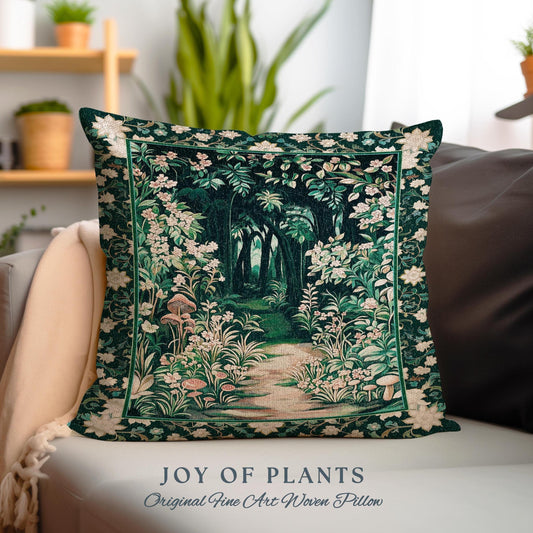 May include: A green and white tapestry pillow with a forest scene. The pillow features a path leading through a forest with trees, flowers, and mushrooms. The text "JOY OF PLANTS Original Fine Art Woven Pillow" is printed below the pillow.