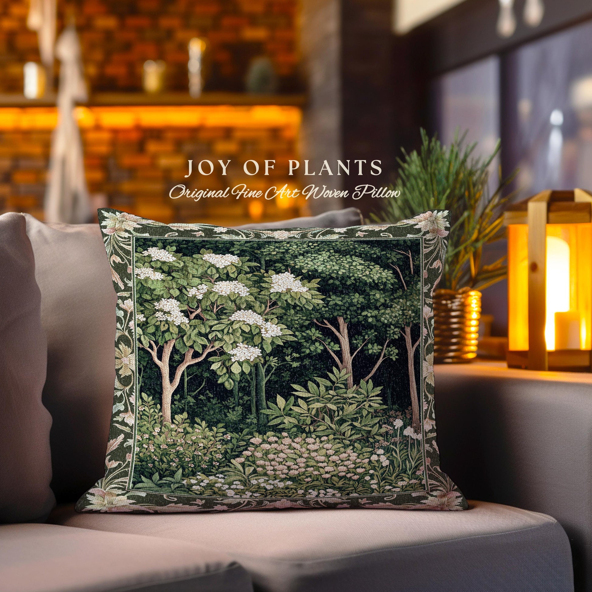 May include: A decorative pillow with a tapestry design featuring a forest scene with trees and white flowers. The pillow is green and white with a brown border. The text "JOY OF PLANTS Original Fine Art Woven Pillow" is printed on the pillow.