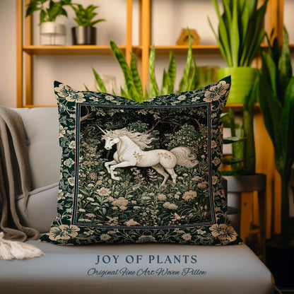 May include: Square decorative pillow featuring a white unicorn in a forest scene. The pillow has a dark green background with floral accents and a cream-colored border. The text "JOY OF PLANTS" and "Original Fine Art Woven Pillow" are at the bottom.
