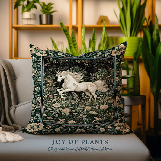 May include: Square decorative pillow featuring a white unicorn in a forest scene. The pillow has a dark green background with floral accents and a cream-colored border. The text "JOY OF PLANTS" and "Original Fine Art Woven Pillow" are at the bottom.