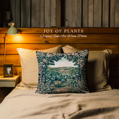 May include: A decorative pillow with a landscape design featuring a forest and a distant view. The pillow is on a bed with other pillows. The text "JOY OF PLANTS Original Fine Art Woven Pillow" is above the pillow.