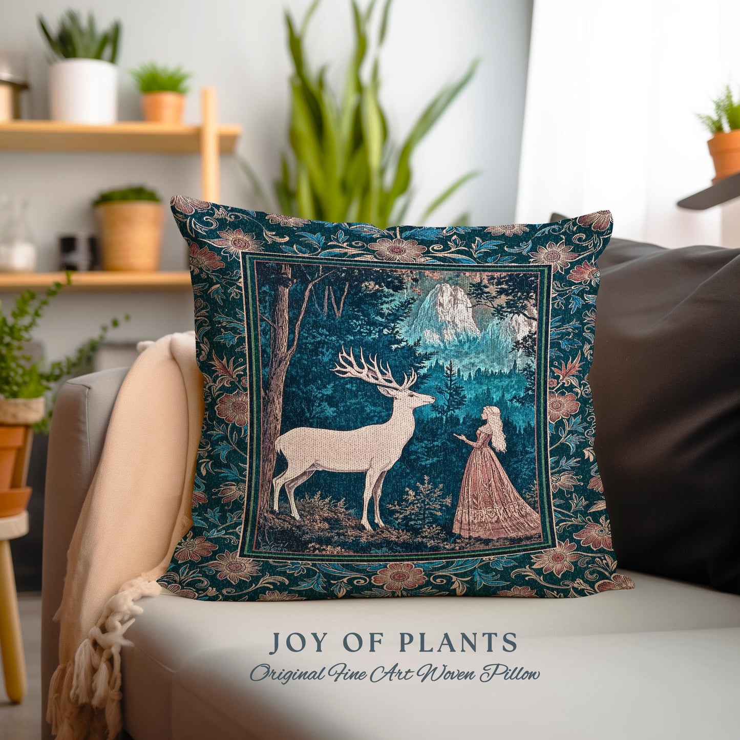 May include: A decorative pillow with a forest scene featuring a white deer, a woman in a pink dress, and mountains. The pillow has a dark teal background with floral borders and the text "JOY OF PLANTS Original Fine Art Woven Pillow".