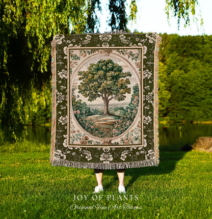 May include: A tapestry throw blanket featuring a detailed tree scene within an oval frame. The blanket has a green floral border and fringe. The text "JOY OF PLANTS Original Fine Art Throws" is at the bottom.