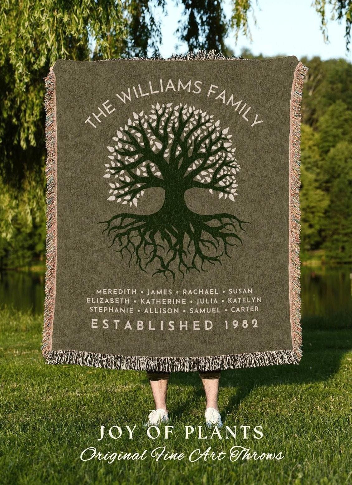 May include: A green family throw blanket with a tree design and the text "THE WILLIAMS FAMILY". The blanket includes names and the year "ESTABLISHED 1982". The bottom reads "JOY OF PLANTS".