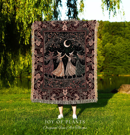 May include: A tapestry throw blanket with a mystical theme. The blanket features a dark burgundy border with floral patterns. The central design depicts four figures in dresses, holding hands under a crescent moon and tree branches. The words 'JOY OF PLANTS Original Fine Art Throws' are at the bottom.