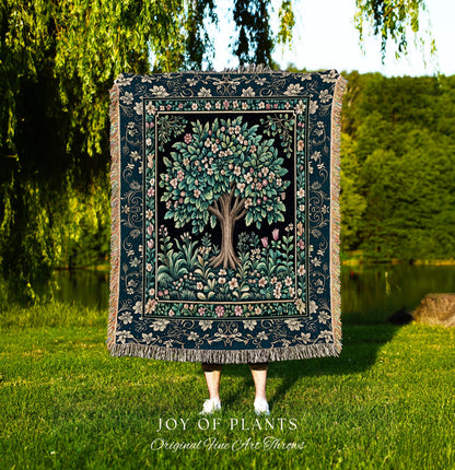 May include: A tapestry throw featuring a detailed tree design with pink and white blossoms, set against a black background. The throw has a dark teal border with floral patterns and fringe. The text "JOY OF PLANTS Original Fine Art Throws" is at the bottom.