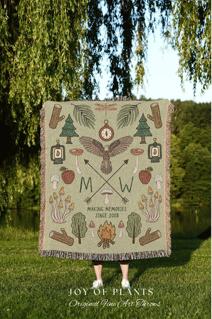 May include: A green throw blanket with a nature-themed design. The blanket features illustrations of trees, mushrooms, a compass, an eagle, and the text "MAKING MEMORIES SINCE 2008". The blanket has a fringed edge.