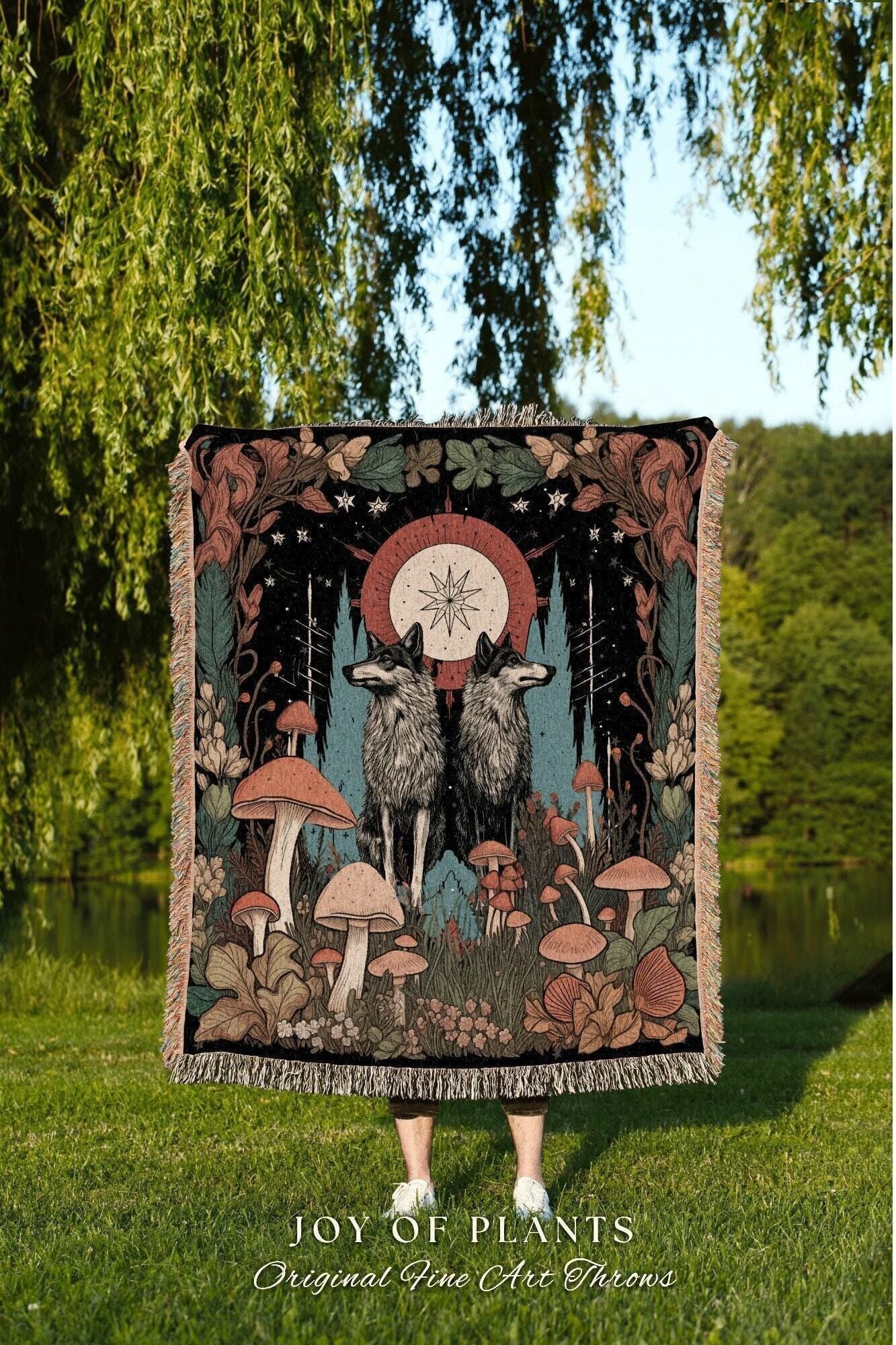 May include: A woven throw blanket featuring a forest scene with two wolves, mushrooms, and a celestial design. The blanket has a black background with a fringed edge and the text "JOY OF PLANTS" and "Original Fine Art Throws".