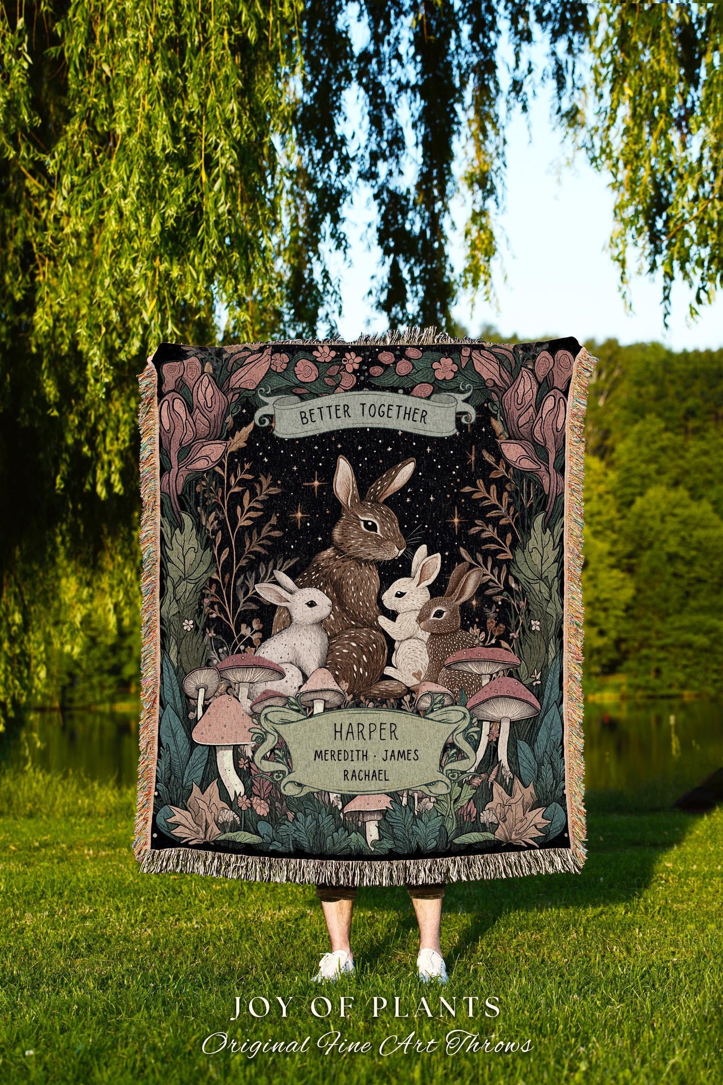 May include: A woven throw blanket featuring a family of rabbits under a starry night sky. The blanket has a fringe border and includes the text "Better Together" and names. The bottom of the blanket reads "JOY OF PLANTS Original Fine Art Throws."