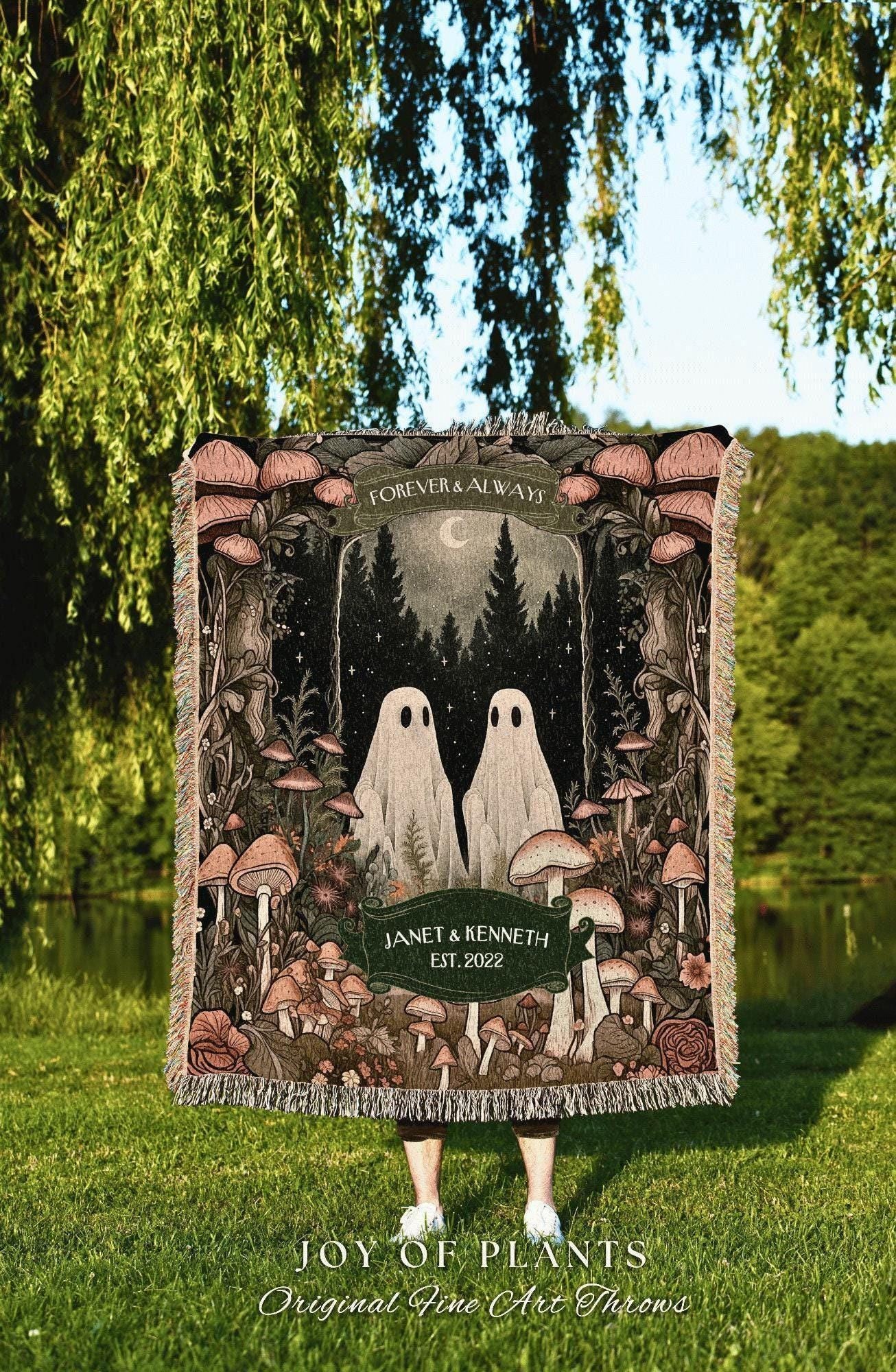 May include: A woven throw blanket featuring a forest scene with two ghost figures. The blanket has a dark background with mushrooms and the text "FOREVER & ALWAYS" and "JANET & KENNETH EST. 2022". The bottom reads "JOY OF PLANTS Original Fine Art Throws".