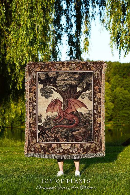 May include: A tapestry throw blanket featuring a red dragon with outstretched wings, perched beneath a large tree. The blanket has a decorative border and fringe. The text "JOY OF PLANTS Original Fine Art Throws" is at the bottom.