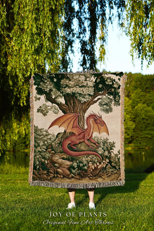 May include: A tapestry throw blanket featuring a red dragon with outstretched wings, resting in a forest setting under a large tree. The blanket has a fringed edge and the text "JOY OF PLANTS Original Fine Art Throws".