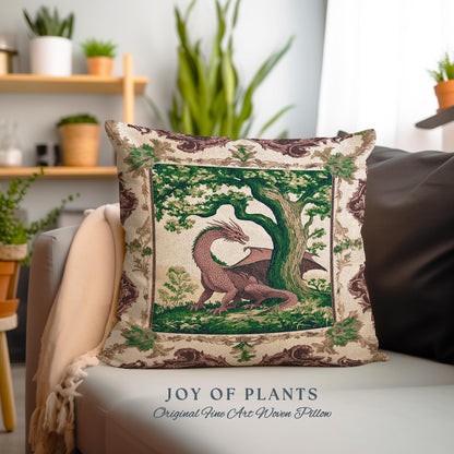 May include: A decorative pillow with a woven tapestry design featuring a green tree and a pink dragon. The pillow has a cream background with a brown and green border. The text "JOY OF PLANTS" and "Original Fine Art Woven Pillow" is printed below the pillow.