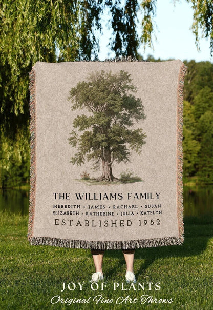 May include: A beige throw blanket with a detailed tree illustration. The blanket features the text "THE WILLIAMS FAMILY" with names and "ESTABLISHED 1982". The bottom reads "JOY OF PLANTS Original Fine Art Throws".