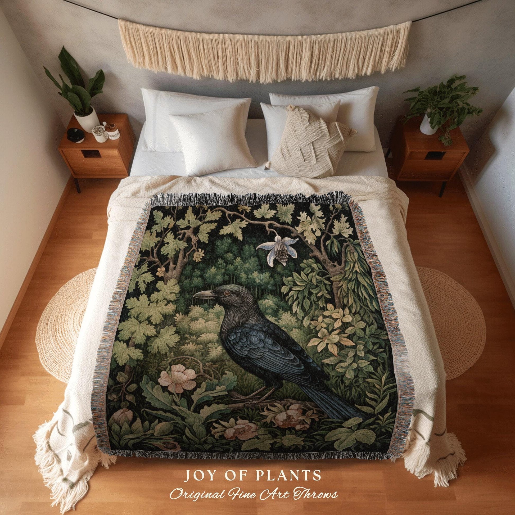 May include: A decorative throw blanket featuring a detailed illustration of a raven in a forest setting. The artwork includes lush greenery, flowers, and trees, with the text "JOY OF PLANTS Original Fine Art Throws" at the bottom. The blanket has a fringed edge.