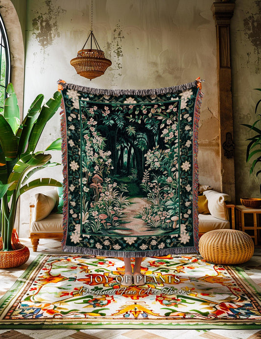 May include: A dark green throw blanket with a forest scene, featuring a path leading into the woods, surrounded by white and pink flowers. The blanket has a fringed edge and is held up in front of a colorful rug.