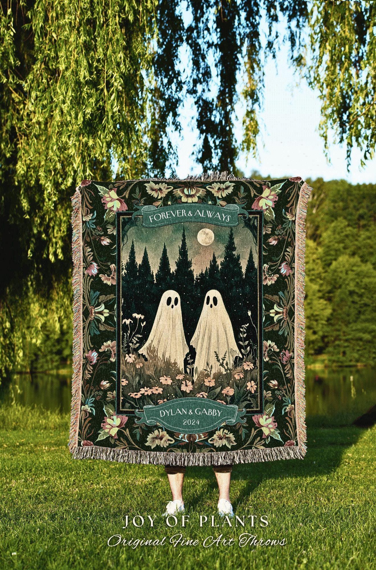 May include: A woven throw blanket featuring a forest scene with two ghost figures, a full moon, and the words "FOREVER & ALWAYS" and "DYLAN & GABBY 2024." The blanket has a dark green background with floral and fringe details. The text "JOY OF PLANTS Original Fine Art Throws" is at the bottom.