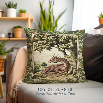 May include: A green and brown woven pillow with a dragon under a tree. The pillow has a green border and a floral pattern. The text "JOY OF PLANTS" and "Original Fine Art Woven Pillow" is printed below the pillow.