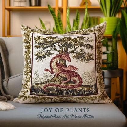 May include: A decorative pillow featuring a tapestry-style design of a red dragon curled around a green tree. The pillow has a cream background with a gold border and the text "JOY OF PLANTS Original Fine Art Woven Pillow".