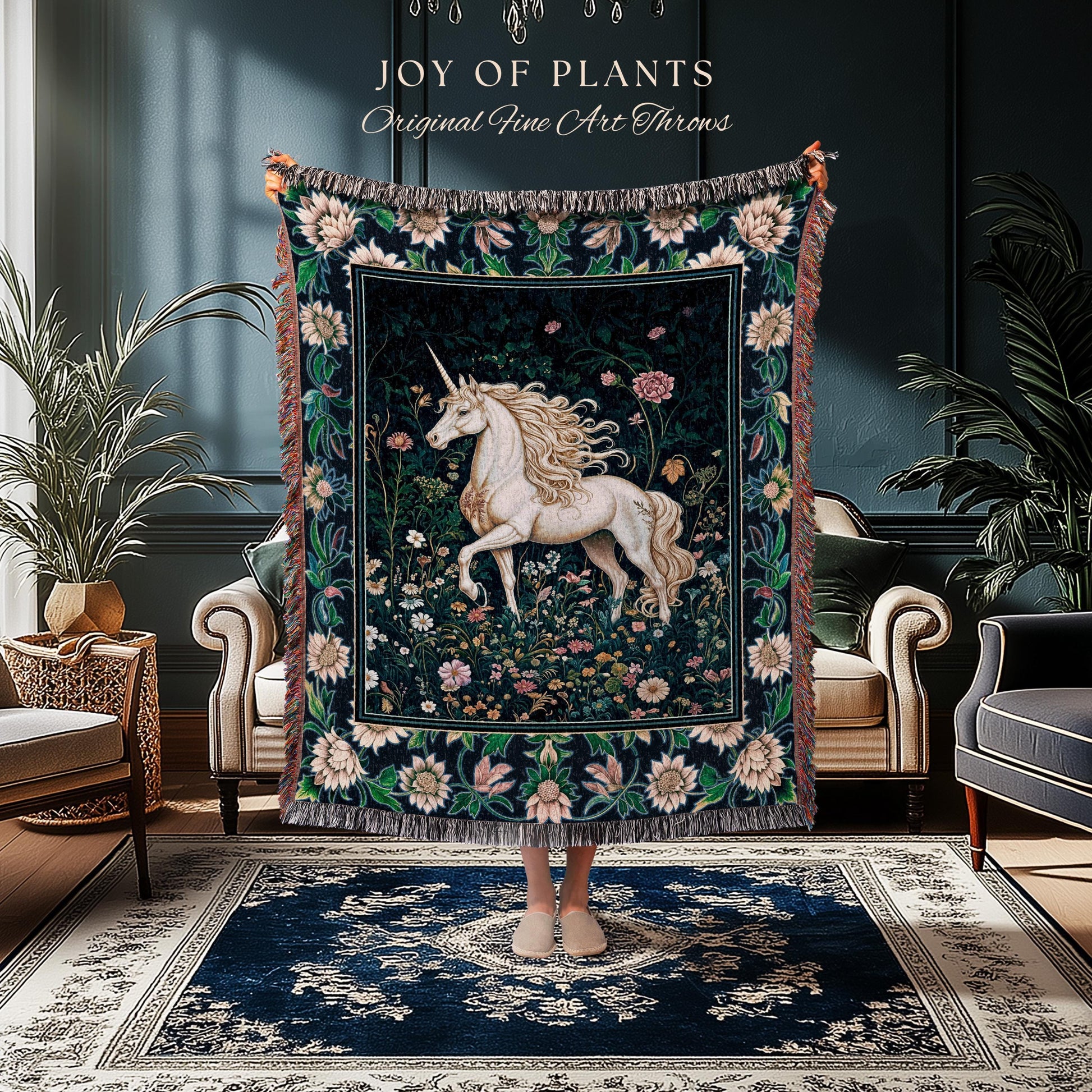 May include: A tapestry throw blanket featuring a white unicorn in a floral garden scene. The throw has a dark background with a border of flowers and fringe. Text at the top reads "JOY OF PLANTS Original Fine Art Throws."