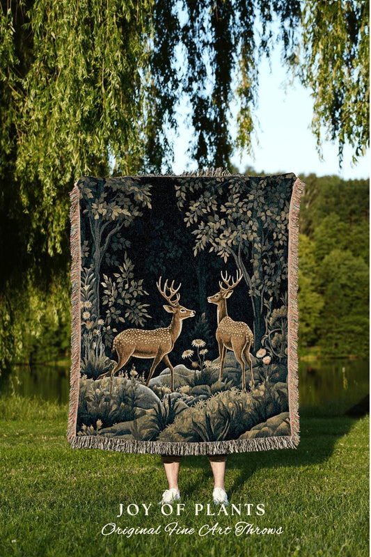 May include: A tapestry throw blanket featuring a forest scene with two deer. The blanket has a dark background with trees and foliage in shades of green and tan. The text "JOY OF PLANTS Original Fine Art Throws" is at the bottom.
