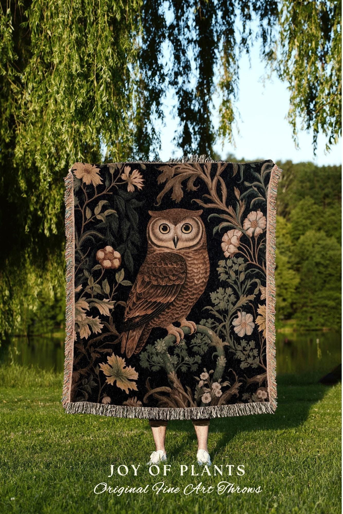 May include: A decorative throw blanket featuring a detailed illustration of a brown owl perched on a branch, set against a black background with floral and foliage accents. The blanket has a fringed edge and the text "JOY OF PLANTS" is visible.