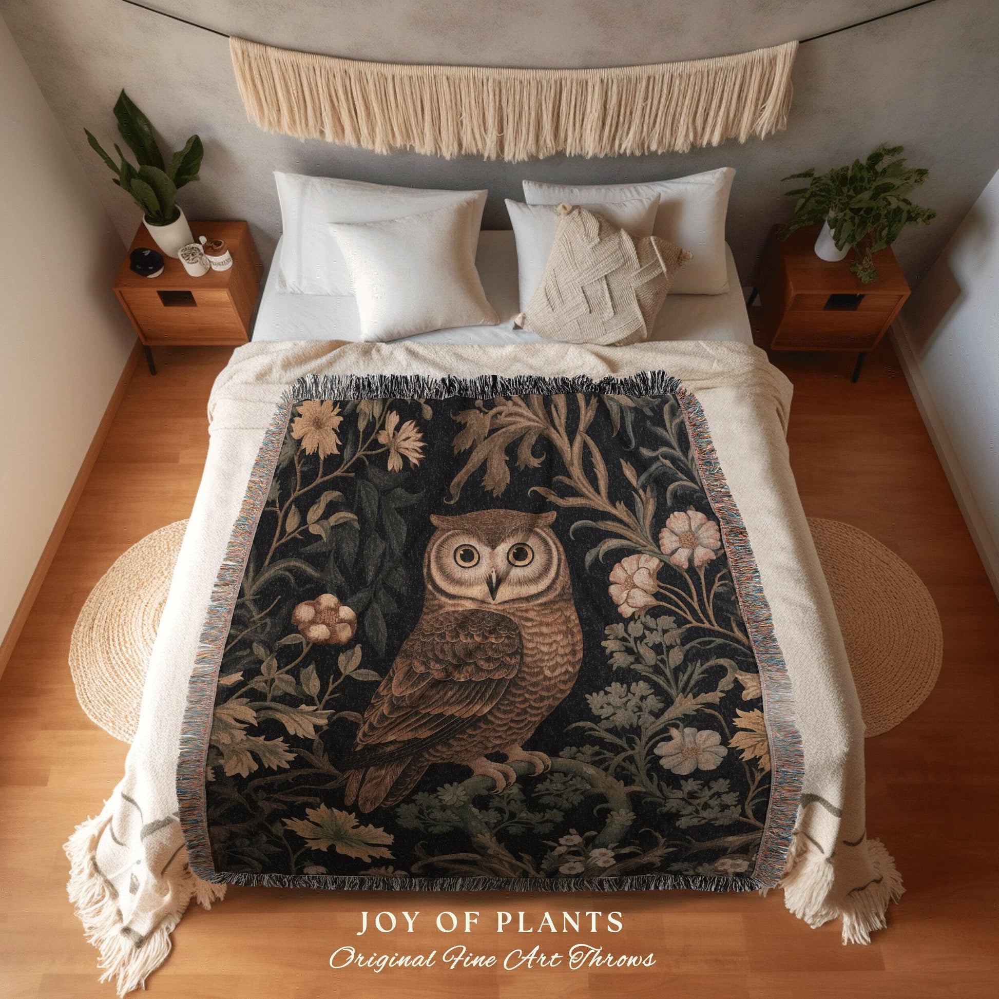 May include: A decorative throw blanket featuring a detailed illustration of an owl perched on a branch, surrounded by floral and foliage elements. The blanket has a dark background with cream-colored fringe and the text "JOY OF PLANTS Original Fine Art Throws".