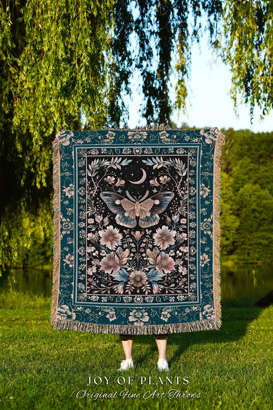 May include: A teal and black throw blanket with a floral and moth design. The blanket features a central moth image with a crescent moon and floral accents. The text "JOY OF PLANTS Original Fine Art Throws" is at the bottom.