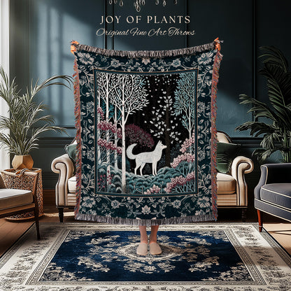 May include: A dark teal throw blanket with a forest scene featuring a white wolf, trees, and pink flowers. The blanket has a decorative border and the text "JOY OF PLANTS Original Fine Art Throws".