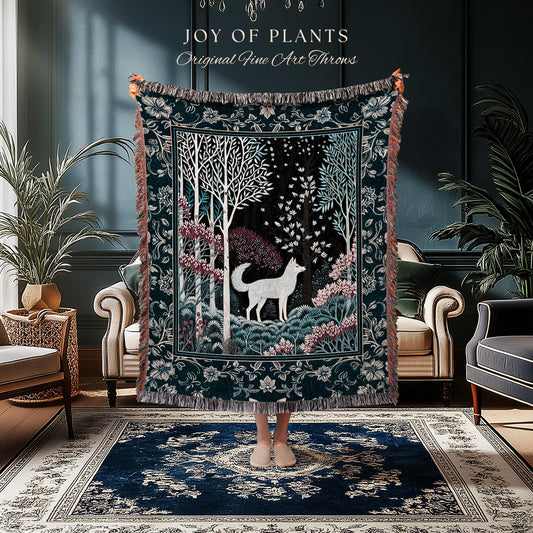 May include: A dark teal throw blanket with a forest scene featuring a white wolf, trees, and pink flowers. The blanket has a decorative border and the text "JOY OF PLANTS Original Fine Art Throws".