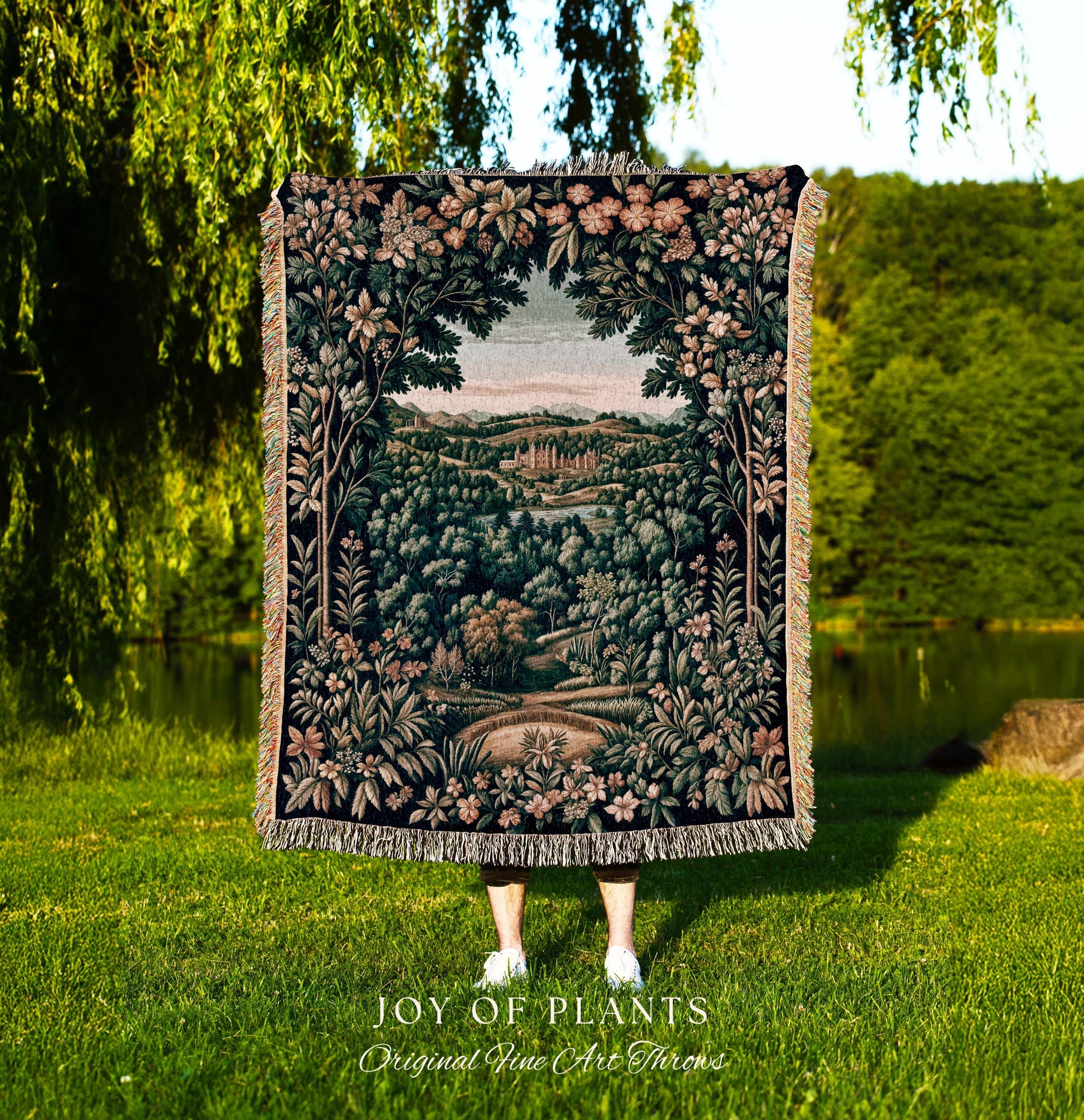 May include: A tapestry throw blanket with a detailed landscape design featuring trees, flowers, and a body of water. The throw is dark with a fringe border. The text "JOY OF PLANTS Original Fine Art Throws" is at the bottom.