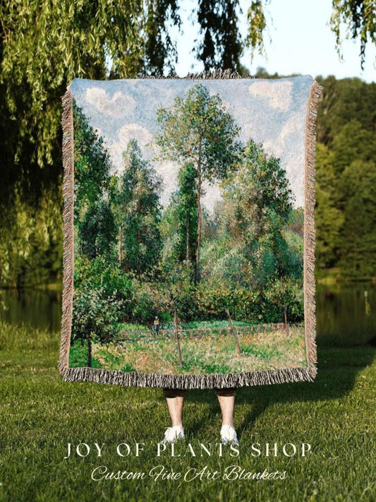 May include: A woven tapestry blanket featuring a landscape painting of a forest scene with trees, a fence, and a cloudy sky. The blanket has a fringed edge and the text "JOY OF PLANTS SHOP Custom Fine Art Blankets" at the bottom.