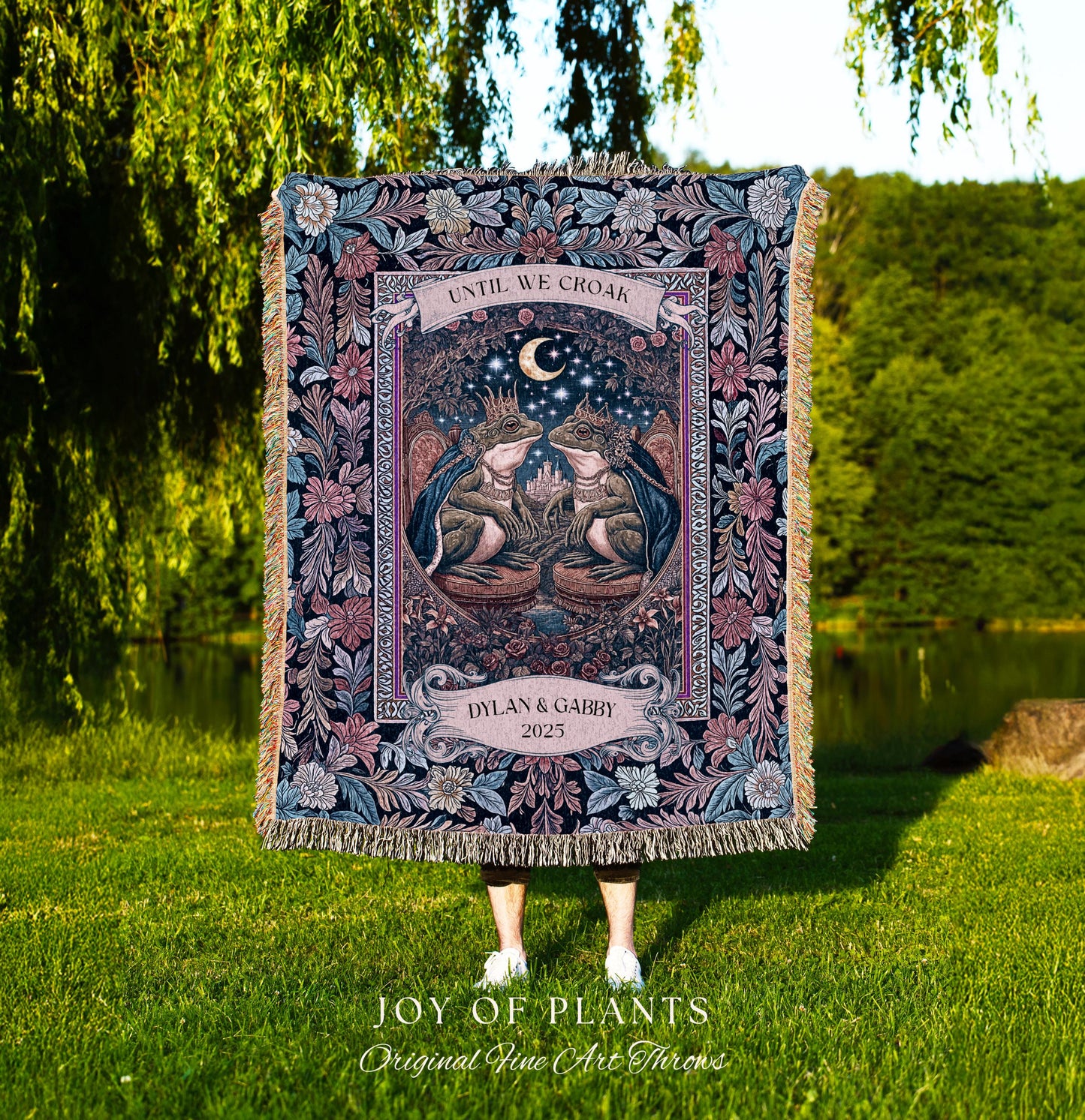 May include: A tapestry throw blanket with a detailed illustration of two frogs wearing crowns, beneath a crescent moon. The blanket features the text "UNTIL WE CROAK" and "DYLAN & GABBY 2025". The blanket has a floral border and fringe.