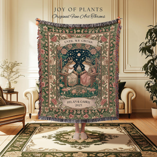 May include: A tapestry throw blanket with a floral border and the text "JOY OF PLANTS Original Fine Art Throws." The central design features two crowned frogs seated on chairs under a starry night sky, with the words "UNTIL WE CROAK" and "DYLAN & GABBY 2025."